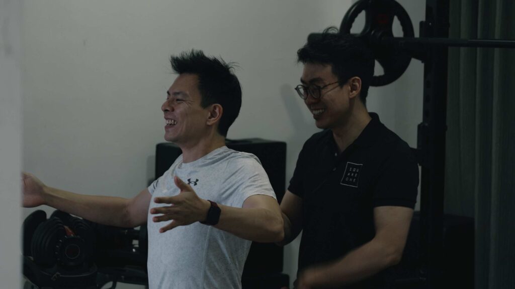 Chiropractor Jesse Cai guiding a client through middle trapezius and rhomboid activation exercises for neck pain rehab.