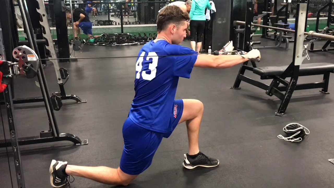Rehabilitation client performing a half-kneeling cable press for shoulder pain and core stability in Singapore.