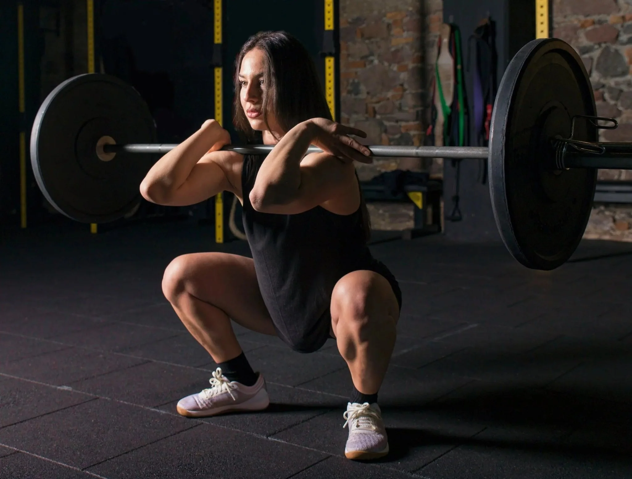 An athlete maintaining strict horizontal elbow alignment during a partial front squat with an empty barbell.