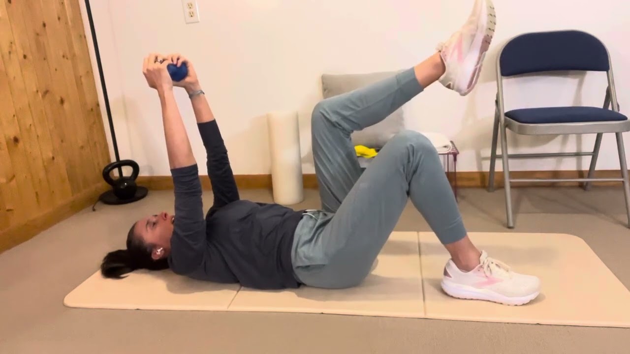 Individual executing a modified deadbug with a serratus reach during a shoulder rehab session in Chinatown Singapore.