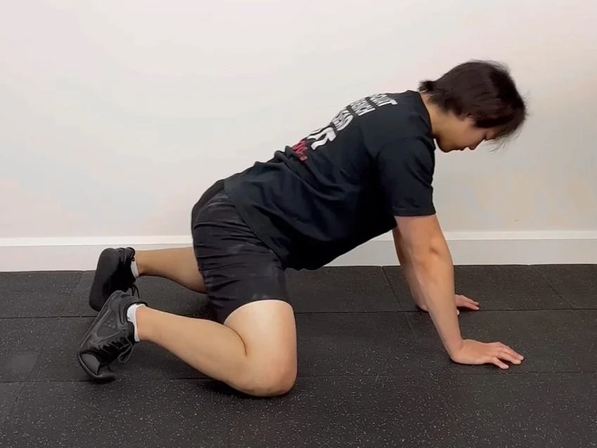 Patient performing quadruped rockbacks for scapular stability at a Singapore active recovery practice.