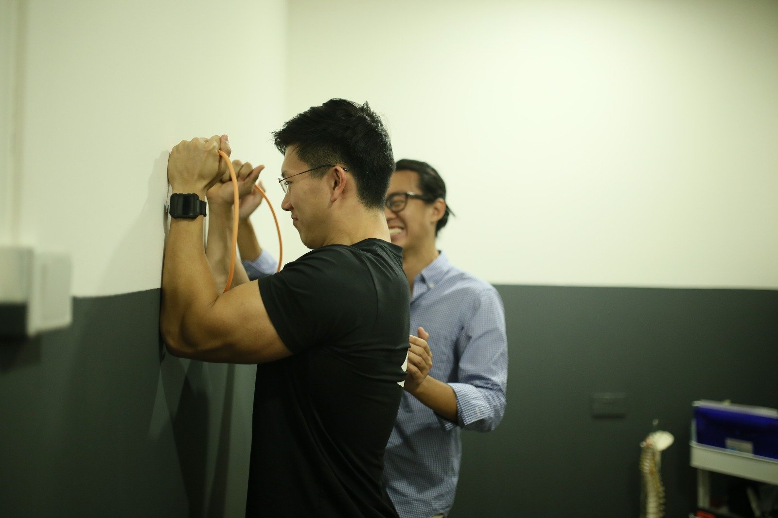 Chiropractor Jesse Cai leading a client through a serratus anterior activation exercise at Square One Active Recovery in Singapore.